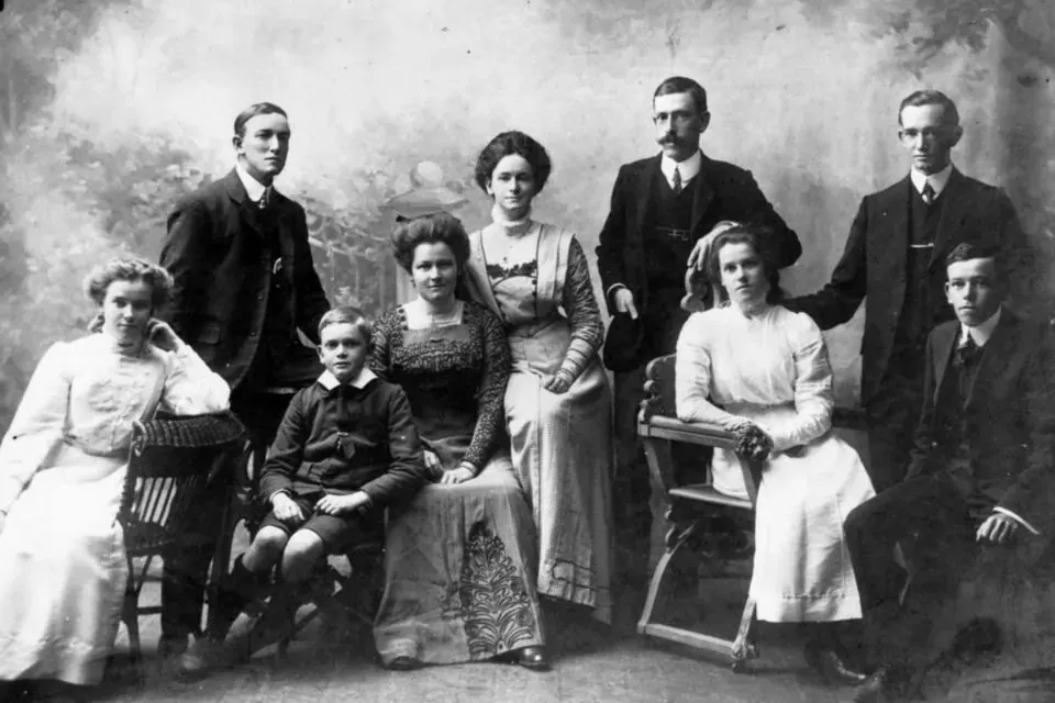 Portrait de famille en noir et blanc pris en studio vers 1910, parents et enfants posant en tenue de cérémonie