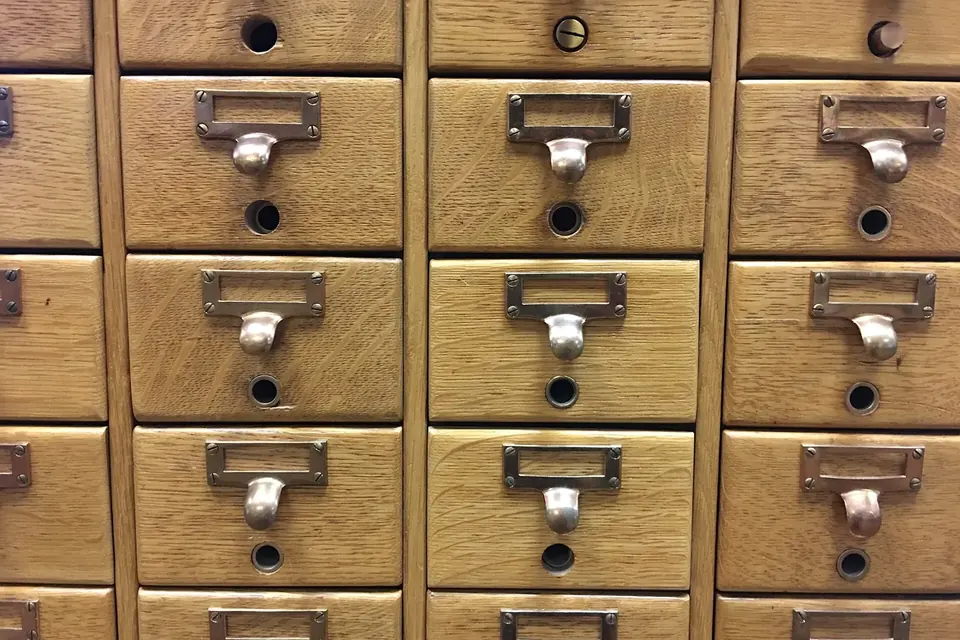Meuble de fichier en bois à nombreux petits tiroirs étiquetés dans une bibliothèque publique