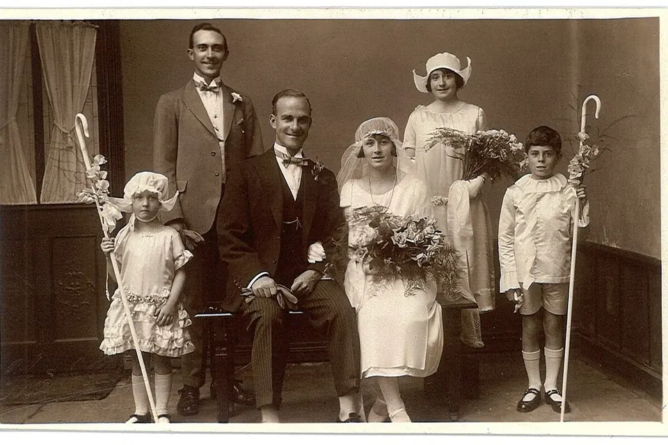 Photographie ancienne d'un groupe de mariage anglais des années 1920 : les mariés au centre, entourés de leur famille en tenue de cérémonie