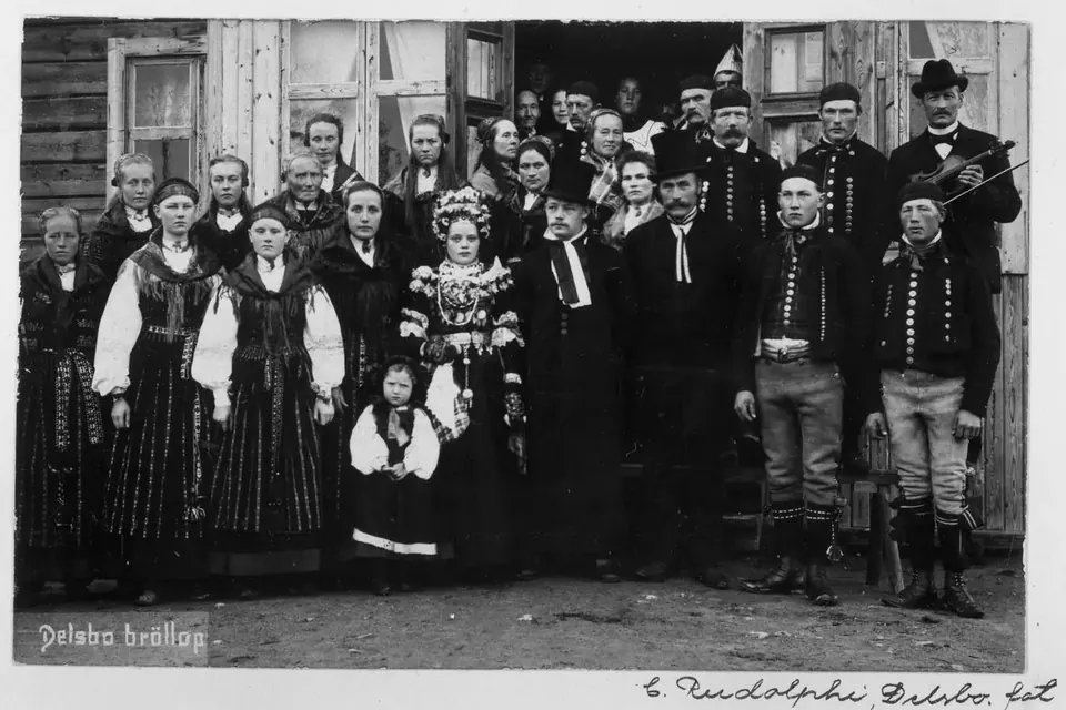 Photographie ancienne d'une noce suédoise : les invités en costume traditionnel posent en plusieurs rangs autour des mariés